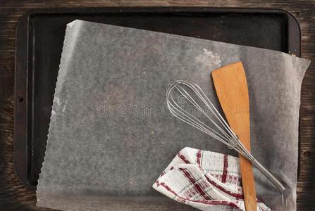 带纸和厨房用具的旧金属烤盘照片